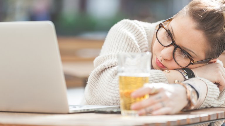 Tired girl with beer and computer in London