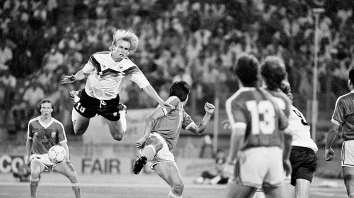 В царството на мръсните номера

Смело може да се каже, че световното първенство през 1990 г. в Италия се явява истинско царство за майсторите на мръсните номера. Циничният футбол с едва 2.21 средно гола в мач е съчетан с ред измамни изпълнения. Както си му е редът, връх на всичко е финалният двубой между Германия и Аржентина. В 65 минута Юрген Клинсман затвърждава репутацията си на футболен мошеник, когато прави невероятно изпълнение на „умиращия лебед”. С падането си той успява да подлъже съдията Едуардо Мендес, който показва на аржентинеца Монсон първия червен картон във всички дотогава световни финали. Не по-малко скандално се явява падането на Руди Фьолер след контакт рамо в рамо с Роберто Сенсини. Минутата е 85-та, а реферът отсъжда дузпа. Андреас Бреме я вкарва, за да донесе титлата на Германия. Още по-смешно става при връчването на наградите. Обявеният за носител на приза за феърплей Гари Линекер отива да стисне ръката на Юрген Клинсман. „Цяло чудо е, че Клинсман не падна при това ръкостискане!”, отбелязва иронично коментаторът на английската телевизия.