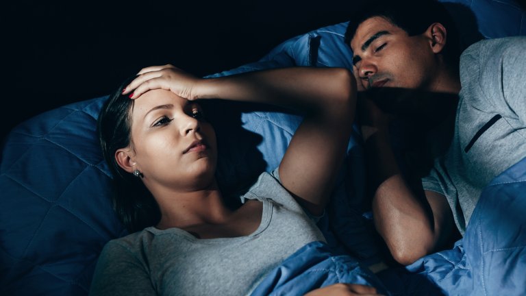 Annoyed woman lying in bed with snoring boyfriend at home in the bedroom