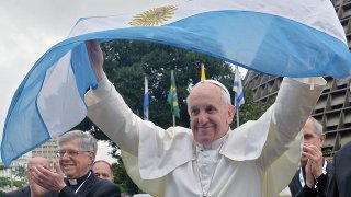 Pope Francis flutters an Argentine flag outside the Metropolitan cathedral in Rio de Janeiro, Brazil on July 25, 2013. The first Latin American and Jesuit pontiff arrived in Brazil mainly for the huge five-day Catholic gathering World Youth Day. AFP PHOTO / LUCA ZENNARO - POOL
