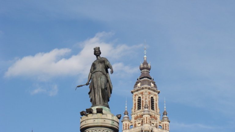 Два от символите на Лил -богинята, която държи фитил на оръдие (статуята е издигната след неуспешната обсада от австрийците през 1792 г.) и кулата на борсата