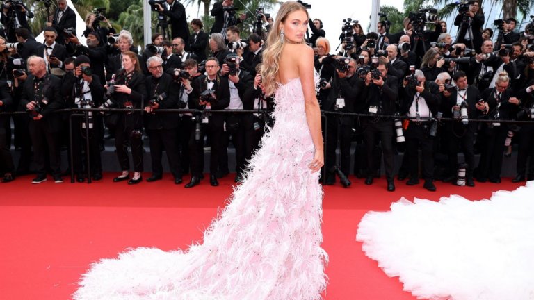 Моделът Роми Стриджид позира в бяла рокля от пера.