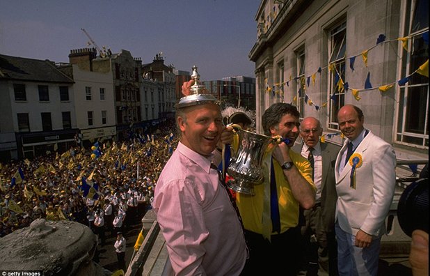Мениджърът на Уимбълдън Боби Гулд и неговият асистент Дон Хау гордо позират с ФА къп след незабравимата победа над Ливърпул на "Уембли" през 1988. Триумфът на "доновете" многократно бе припомнян през последните дни, след като Уигън успя да победи многомилионния Манчестър Сити, което бе прието като най-големия шок в надпреварата от четвърт век насам.