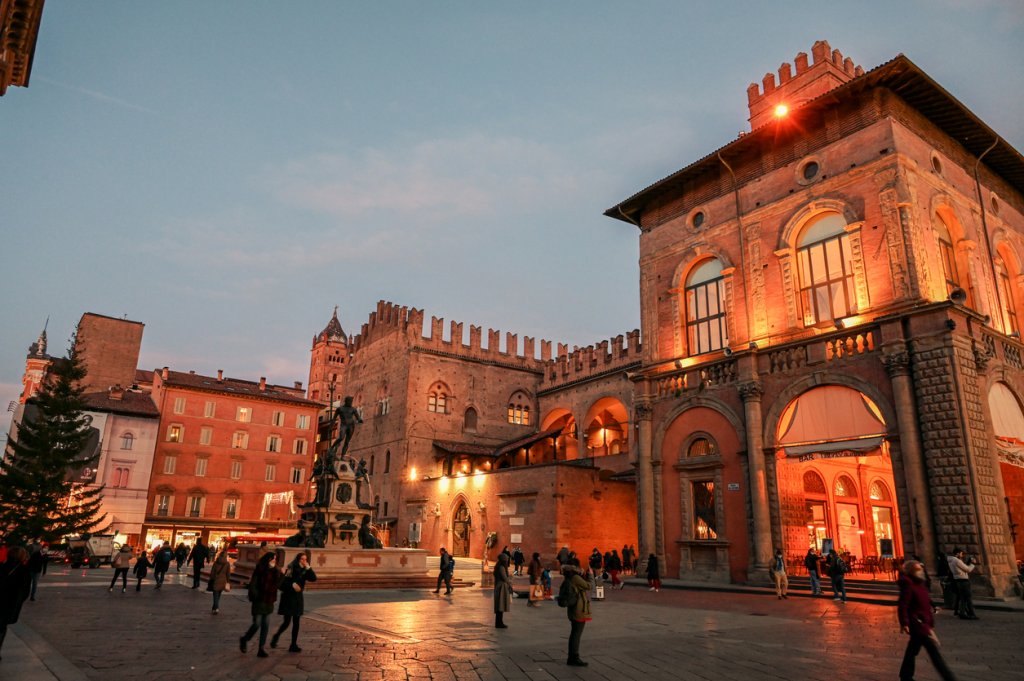 Пиаца дел Нетуно, БолоняБолоня е красотата на Емилия Романя, потънала в червено заради характерните фасади и тухли. А нейният център е пиацата, отново с Нептун в средата на фонтана. Почти всички главни забележителности на Болоня са около този площад, макар че той е и средище за почивка и похапване след туристическите обиколки.