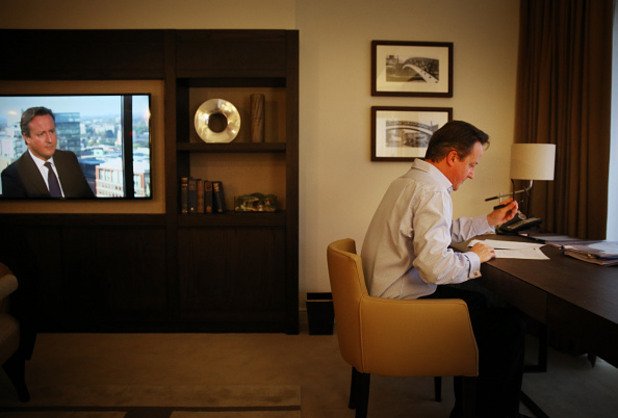 Британският премиер дейвид Камерън подготвя речта си за конференцията на Консервативната партия на 30 септември в хотелска стая в Бирмингам, а на екрана се появя образът му.