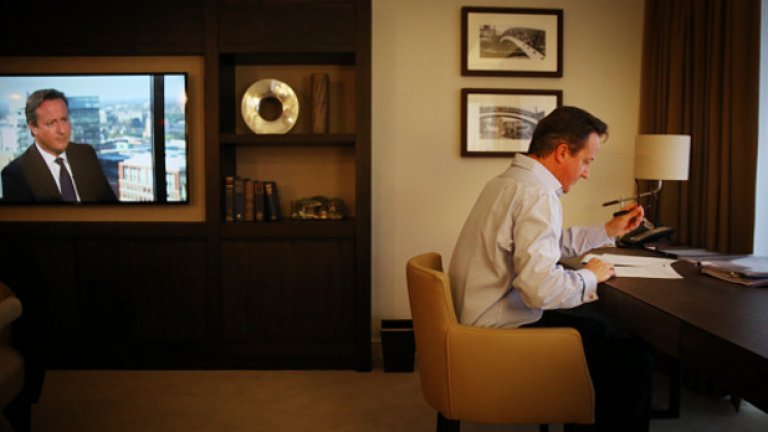 Британският премиер дейвид Камерън подготвя речта си за конференцията на Консервативната партия на 30 септември в хотелска стая в Бирмингам, а на екрана се появя образът му.