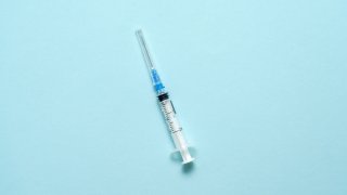 Top view of injection syringe on blue background. Minimal vaccine concept. Medical treatment of diabetes with insulin. Covid-19 vaccination. Antivax campaign
