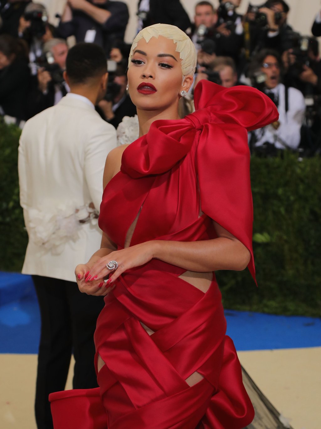 Червеното е цвят, доминантен за Met Gala 2017. Рита Ора е блечена в рокля, която напомня голяма червена панделка с плитка на края. 