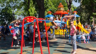 Children in the presence of their parents ride on a swing on the playground at the weekend