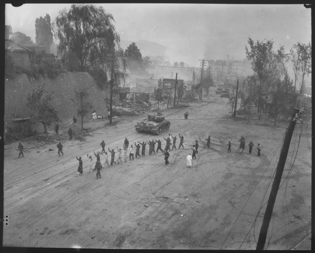 A_U.S._Marine_tank_follows_a_line_of_prisoners_of_war_down_a_village_street._-_NARA_-_532408.tif