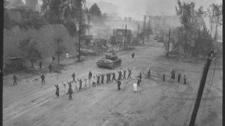 A_U.S._Marine_tank_follows_a_line_of_prisoners_of_war_down_a_village_street._-_NARA_-_532408.tif