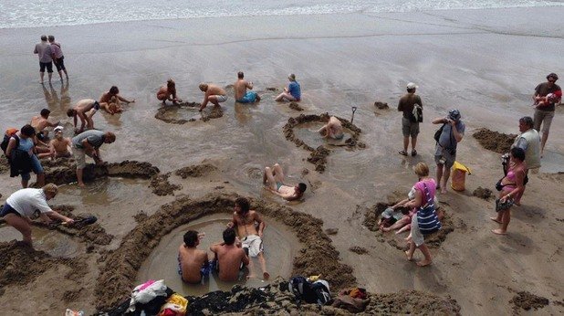 Посетителите на този новозеландски плаж се възползват от топлите извори, които проникват през пясъка, и често си изравят големи дупки, за да се поплицикат в горещите води