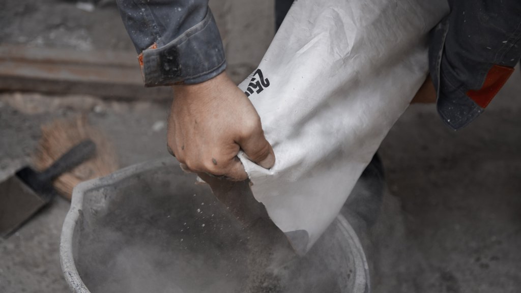 Construction worker pouring the cement to the bucket