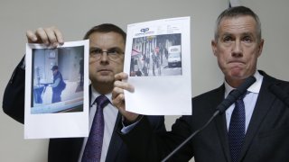 Paris prosecutor Molins and director of the Paris' judiciary police Flaesch show two photographs of the suspect gunman taken from surveillance footage  during a news conference in Paris