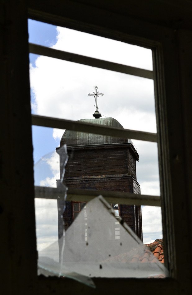 Камбанарията на местната църква наднича през изпочупените стъкла на един от прозорците.