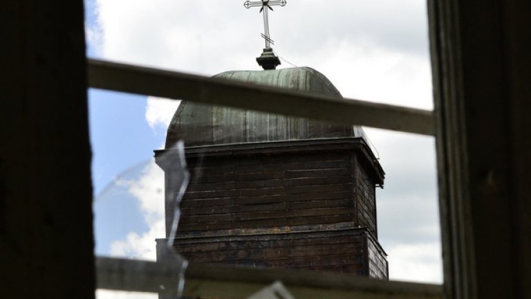 Камбанарията на местната църква наднича през изпочупените стъкла на един от прозорците.
