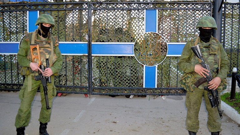 Трима въоръжени без опознавателни знаци пазят входовете на украинската военноморска база. Предполага се, че са руски войници