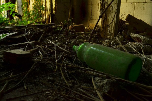 Стъклена бутилка от олио от близкото минало лежи върху влажния под на банята