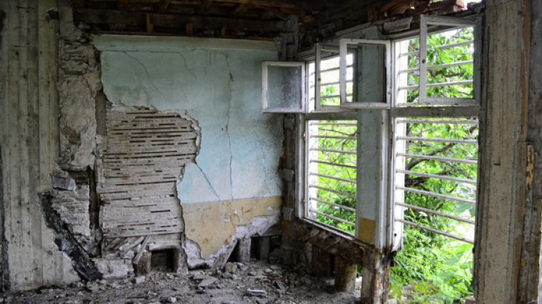 Текст: Кирпичената мазилка се руши и оголва следите от някогашен ремонт  - дървесината на част от стената е заменена с цимент.