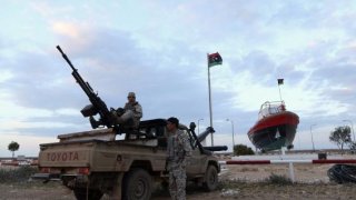 Rebels stand guard at the entrance of the Es Sider export terminal where a North Korean-flagged tanker has docked in Ras Lanuf