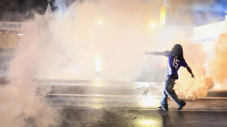 Мъж връща обратно към полицаите една от димките, с които те разпръсват протестиращите