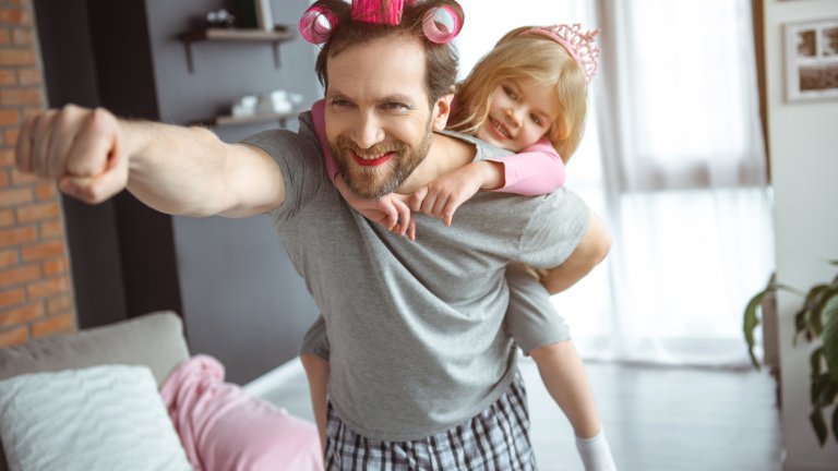 Cheerful parent playing a super hero with girl