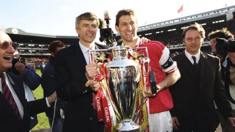 1997/98: Първата титла на Венгер
Този сезон треньорът на Арсенал се очаква да подобри рекорда на Фъргюсън за най-много мачове начело във Висшата лига. Всичко започна много отдавна – и по точно, когато спечели първата си титла на Англия. На снимката Венгер празнува заедно с капитана на Арсенал Тони Адамс трофея на 3 май, 1998-а. По-късно френската революция в тима доведе до дубъл.