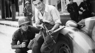 1030px-American_officer_and_French_partisan_crouch_behind_an_auto_during_a_street_fight_in_a_French_city._-_NARA_-_531322_-_restored_by_Buidhe