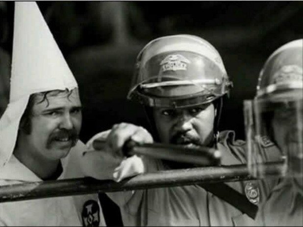 Тъмнокож полицаи предпазва член на Ку Клус Клан от простестиращи, 1983 година