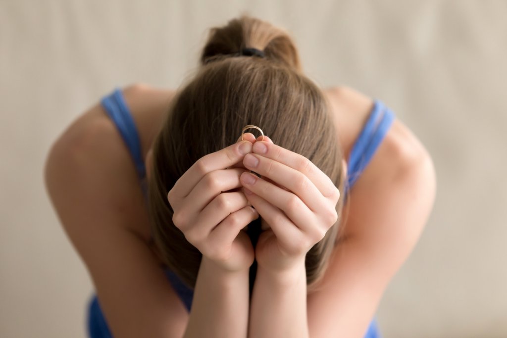 Woman with broken heart holding wedding ring