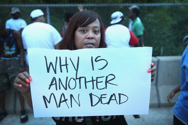 Протестираща жена с надпис, гласящ "Защо още един човек е мъртъв"