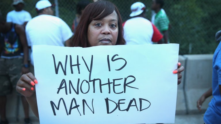 Протестираща жена с надпис, гласящ "Защо още един човек е мъртъв"