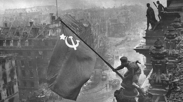 Втората световна война е най-големият и разрушителен конфликт, който светът някога е виждал. Когато руските войски превземат Райхстага в Берлин - този символ на германското лидерство, камерите също присъстват. 

Превземането на сградата не става при най-добрите условия за снимки, така че Червената армия разиграва събитието два пъти. Фотографът Евгени Халдей запечатва днес емблематичния образ на руския войник, който пази бойното знаме на СССР. 

Всъщност, това не е оригиналната снимка. От нея са заличени любопитни детайли, като ръчния часовник на един от руските военни, за да се прикрие разграбването, което правят редниците на Червената армия