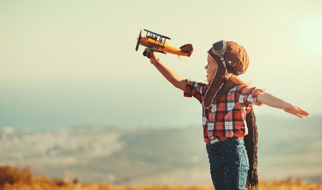 Child pilot aviator with airplane dreams of traveling in summer  at sunset