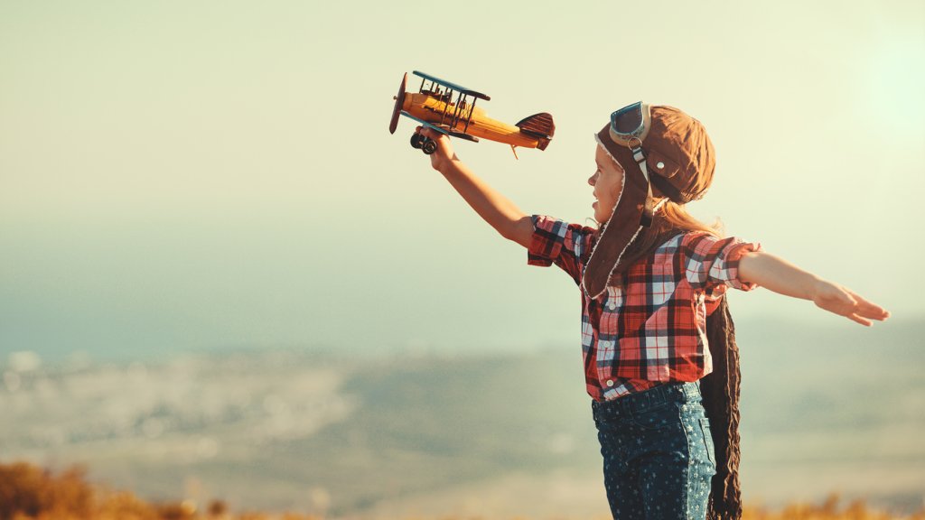 Child pilot aviator with airplane dreams of traveling in summer  at sunset