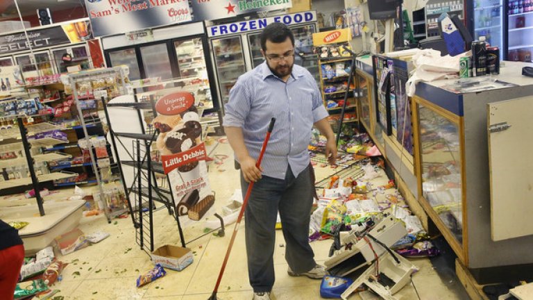 Собственикът на магазина почиства след погрома