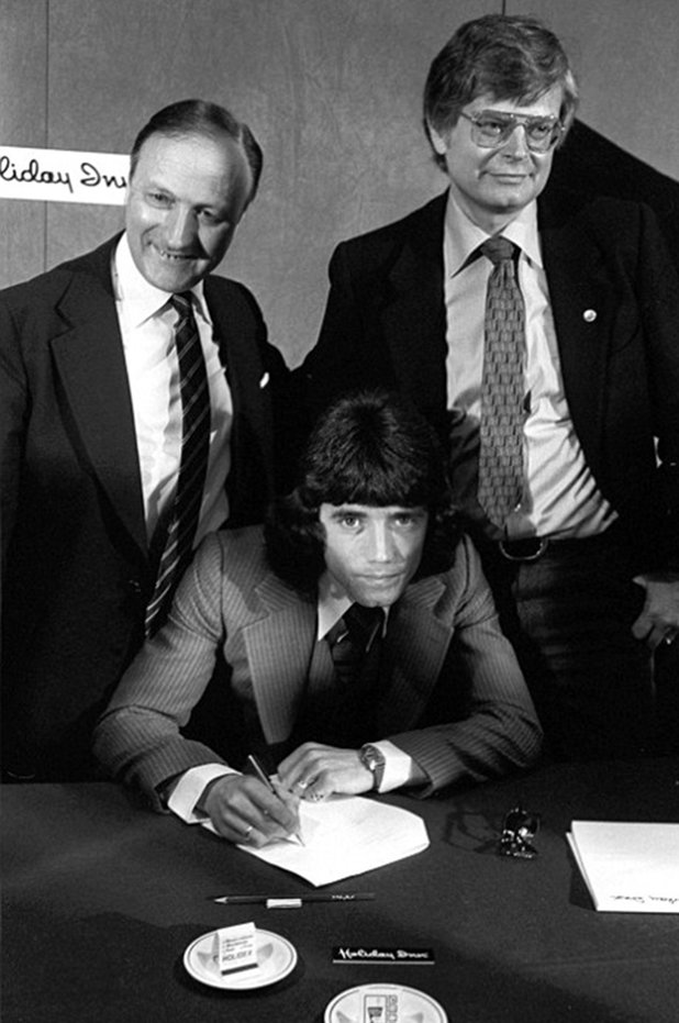 Кевин Кийгън гледа право в обектива, подписвайки с Хамбургер. Ливърпул го продаде за 0.5 млн. паунда през 1977-а, а босовете на двата клуба Джон Смит и Петер Крон бяха удовлетворени от сделката.