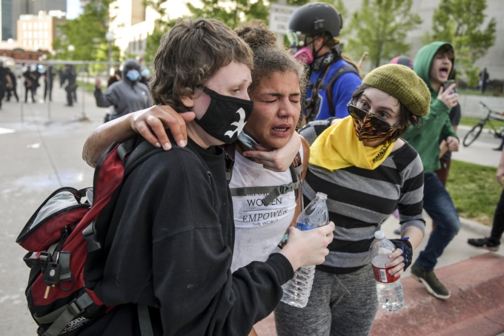 Жена, получава помощ от протестиращи, след като е била напръскана с лютив спрей по време на протеста в Денвър.