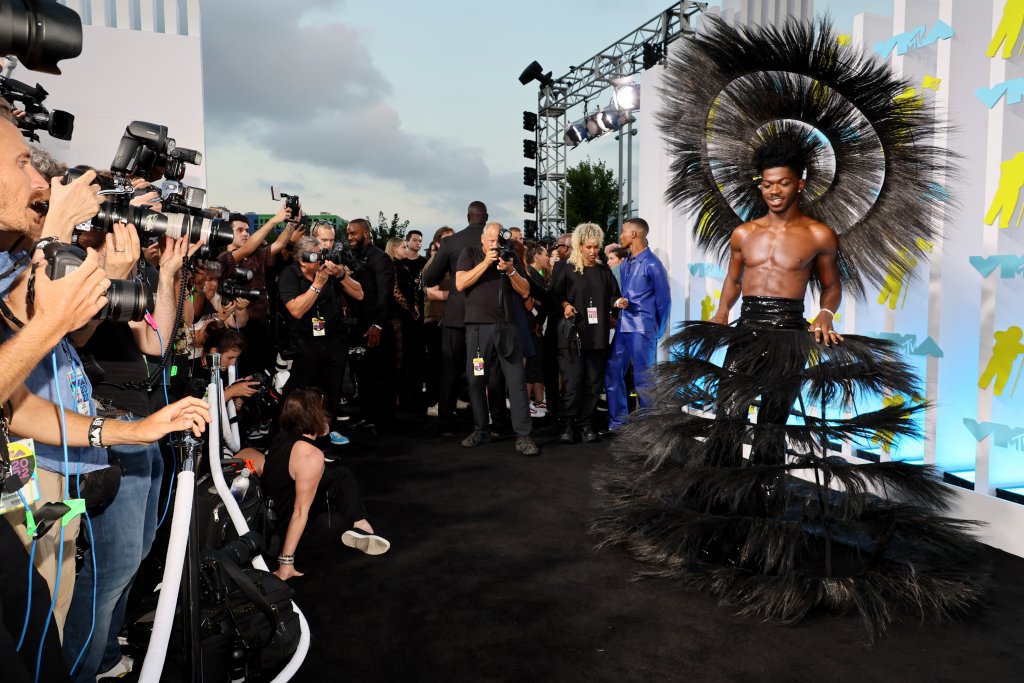 Lil Nas и голата готика
Изглежда изпълнителят Lil Nas е бил в настроение за готик Коледа през август, пристигайки на VMA, облечен като черна коледна елха. Тоалетът е дело на дизайнера Haris Reed, който е опитал да събере всички провокативни идеи за стила в една дреха - мъжка пола от пера, впити кожени панталони, свалено горнище и за капак - обемиста корона, която превърна Lil Nas във фешън магьосника на събитието.