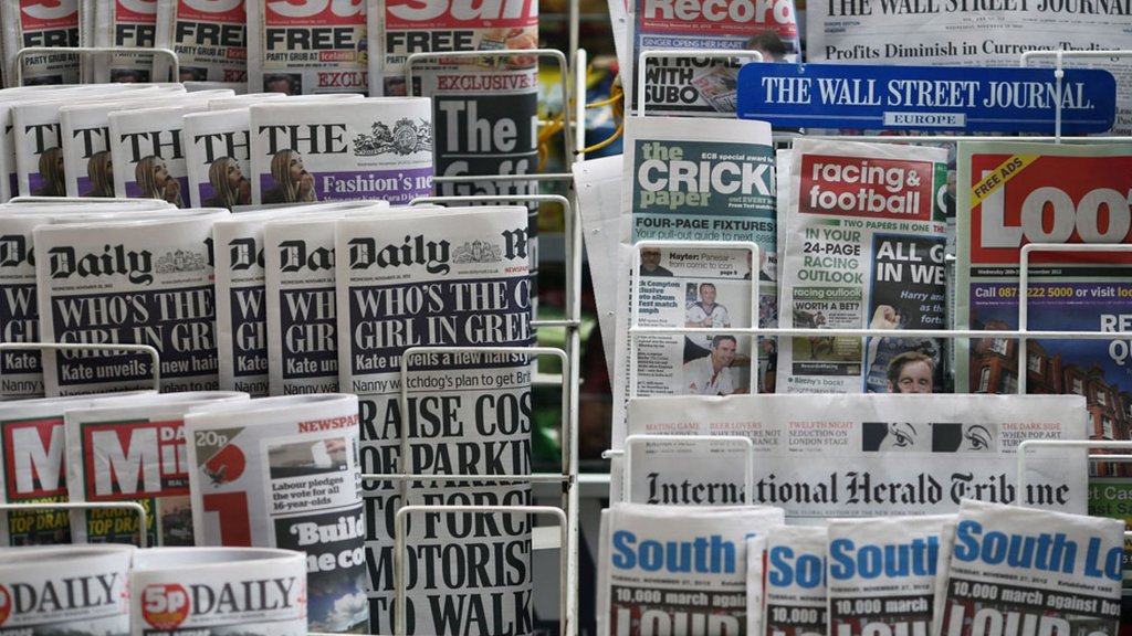 Newspapers are displayed on a stand outside a newsagent -1464267