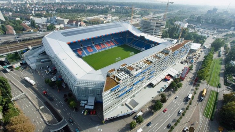 8. Футболната арена „Санкт Якоб”
Ако в Швейцария най-митичният стадион е „Ванкдорф” в Берн, където през 1954 г. се играе финалът на световното между ФРГ и Унгария (3:2), днес „Санкт Якоб” в Базел се явява нещо като сърцето на футбола в страната. Арена не само за местния шампионски тим, но и на националния отбор. 40-хилядното съоръжение е построено между 1999 и 2001 г. срещу инвестиция от 220 милиона швейцарски франка, отдавна покрити от таксите на триетажния търговски център „Манор”, вграден в трибуните. Нещо повече – в едната от фасадите на „Санкт Якоб” има не само офиси, но и апартаменти, в които живеят инвалиди. По законите в страната това води до данъчни облекчения за търговското дружество „Базел Юнайтед”, което е собственик на стадиона. Хитро измислено!
Над 600 000 души посещават стадиона и търговския център всяка година, което осигурява около 70% от приходите на футболния клуб. На „Санкт Якоб” се провежда и откриването на Евро 2008, чието домакинство бе поверено на Швейцария и Австрия. На същото първенство управата на стадиона осъществи безпрецедентна акция по смяна на терена, който бе станал на парцали заради проливния дъжд на мача Швейцария – Турция (1:2). Новите чимове бяха поръчани от Холандия още на полувремето, след като се видя, че игрището загива. 26 камиона потеглиха веднага към Базел, а само за 24 часа работа цялата трева беше подменена с нова.