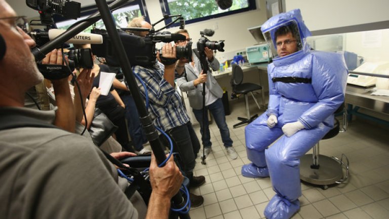 Един от лекарите с изолационен костюм обяснява на журналисти процедурата по лечение на ебола