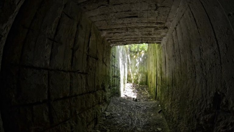 Светлина в тунела. Въпреки здравината си, железобетонните стени на бункера се рушат от времето и затрупват пода на този коридор.