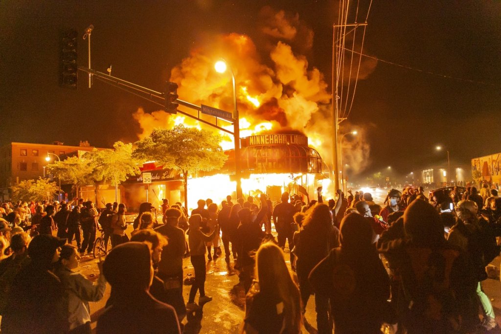 Протестиращи стоят пред запален магазин в Минеаполис.