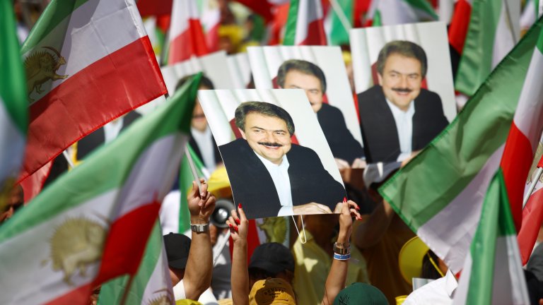 Протестиращи ирански имигранти в Берлин държат плакати на бившия лидер на МЕК Масуд Раджави