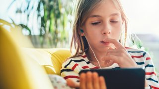 Little girl sitting on sofa and using smart phone