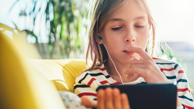 Little girl sitting on sofa and using smart phone