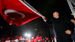 Мевлют Чавушоглу на сцената на резиденцията в Хамбург, развява турския флаг 