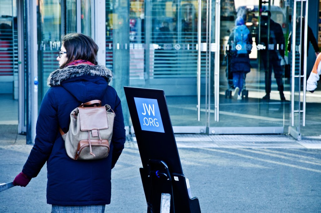 A female Jehovah's Witness member on an outreach programme outside the entrance of Berlin Hauptbahnhof (Main Train Station)  - Germany.