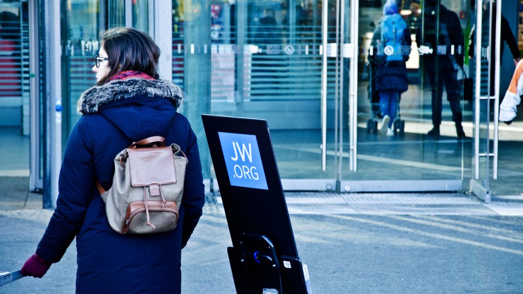 A female Jehovah's Witness member on an outreach programme outside the entrance of Berlin Hauptbahnhof (Main Train Station)  - Germany.